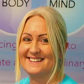 Smiling blonde woman in teal scrubs at wellness event