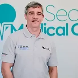 Man in polo shirt smiling in front of medical center sign