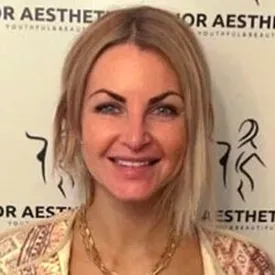 Smiling blonde woman in front of aesthetics clinic backdrop