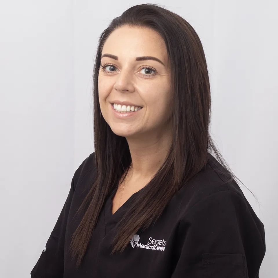 Smiling female healthcare professional in black Secrets Medical Centre scrubs