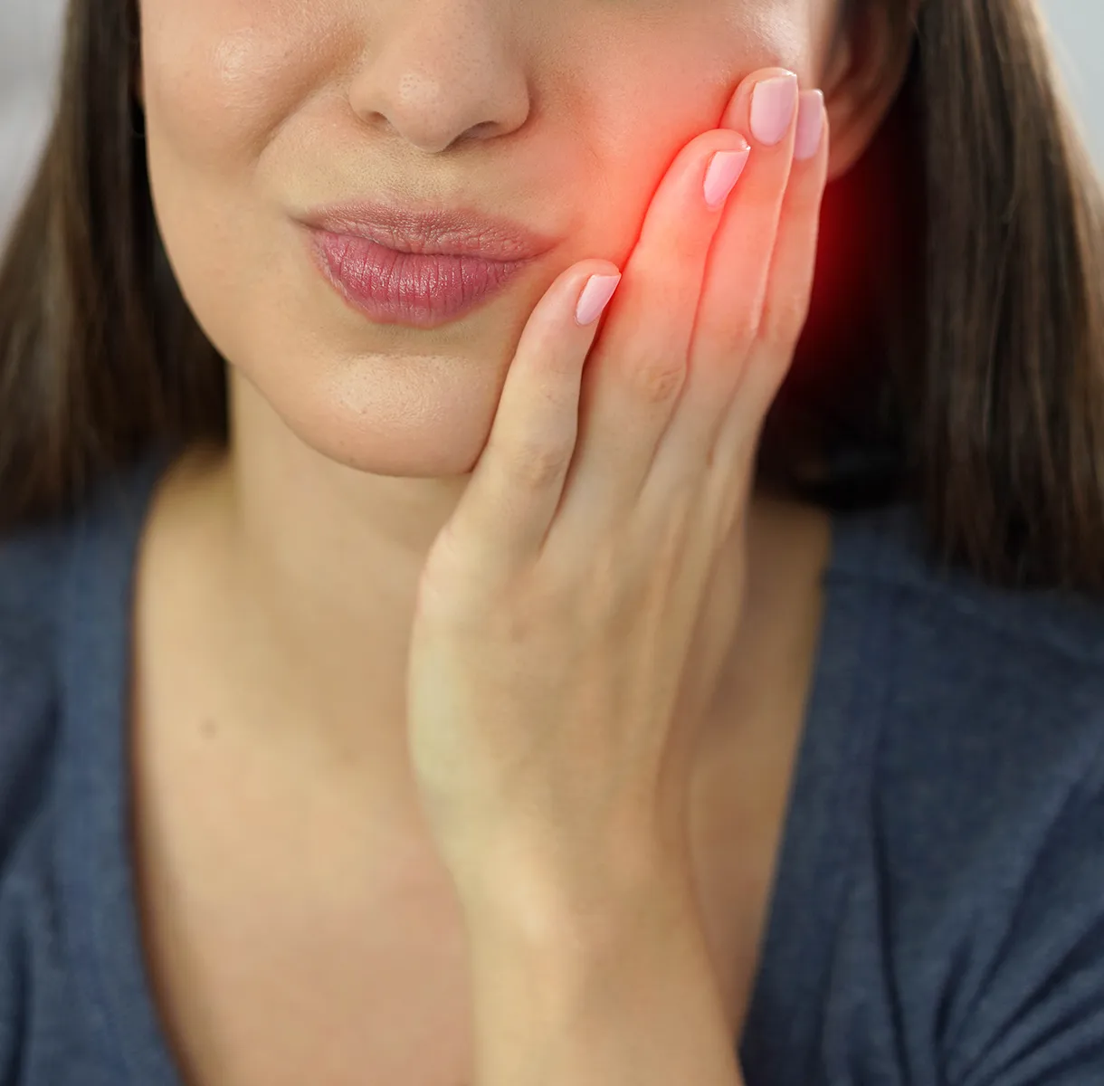 Woman holding jaw with red glow indicating tooth pain