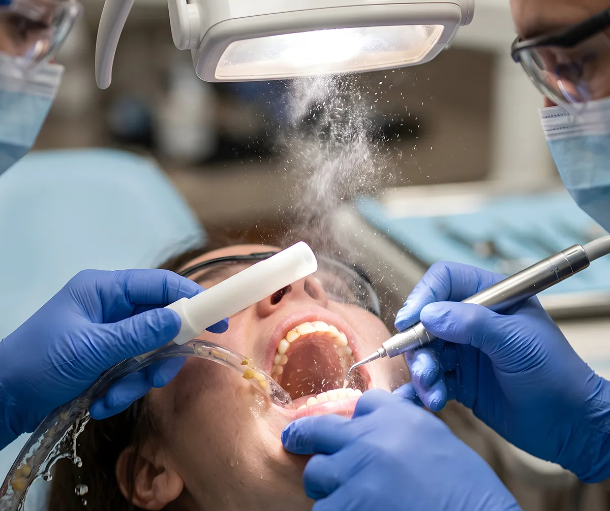 Dentist performing dental procedure on patient with tools